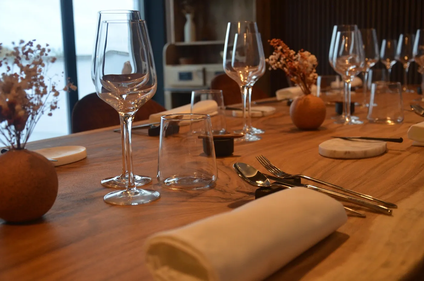 La table dressée : verres, serviette roulée et couverts sur le bois